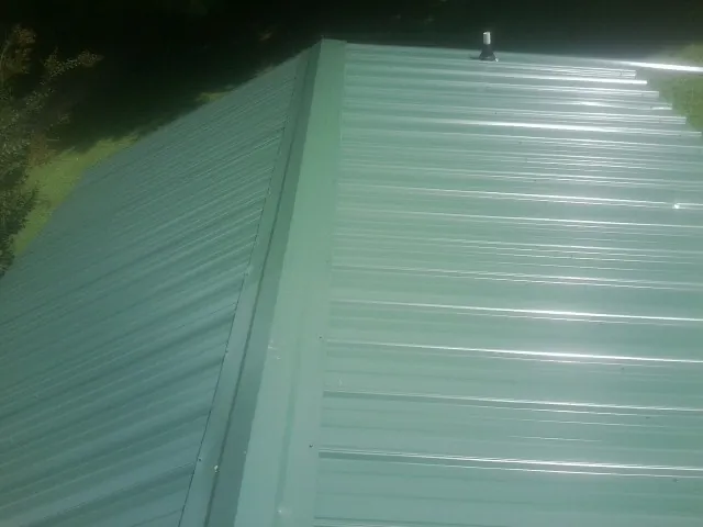 New green metal panels meeting at the ridge of a roof — Flat Roof Repair work by our crew in Riverhead