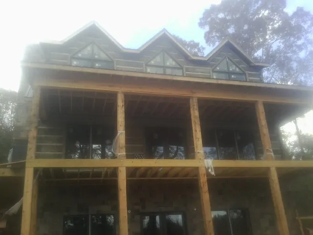 Dormers and porch framing on a large log home under construction — Roof Coating work by our crew in Riverhead