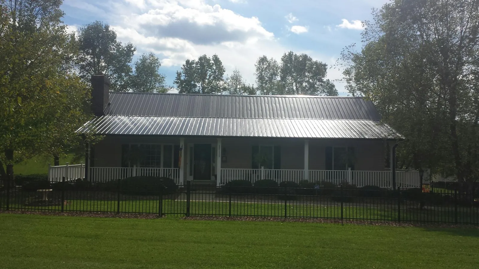 Gray metal roof on a brick ranch with a full width front porch — Gutter Guard Installation work by our crew in Riverhead